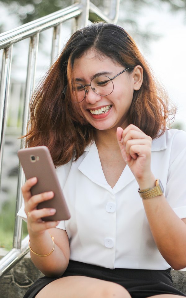 Student smiling at her phone by a window