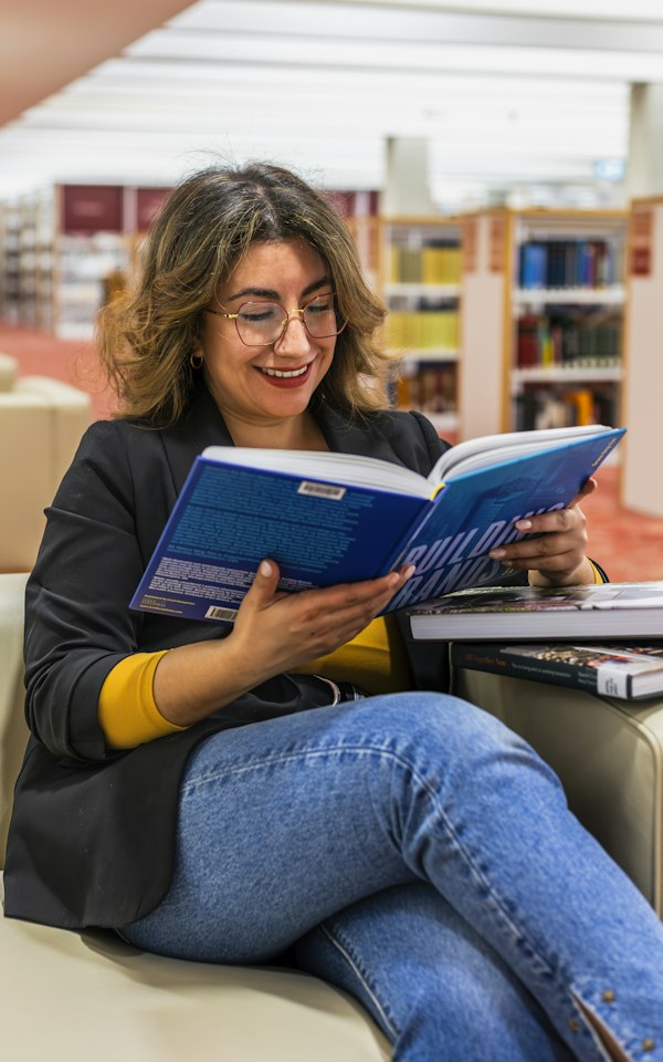 Student smiling while reading in a library